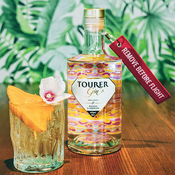 Tourer mango gin perfect gin & tonic garnished with fresh mango and hibiscus flower